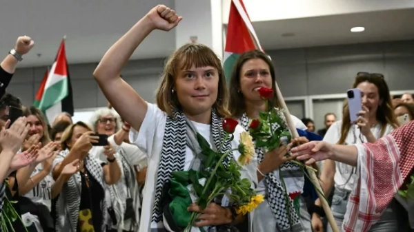 Шведська активістка із захисту клімату Грета Тунберг піднімає кулак після прибуття разом із активістами, які пливли на борту суден з гуманітарної флотилії, що прямувала до Гази, перш ніж їх зупинили та затримали ізраїльські війська, яких зустрів натовп прихильників, у зоні прибуття міжнародного аеропорту Афін 6 жовтня 2025 року. Міністерство закордонних справ Греції повідомило, що 161 громадянин з 16 європейських країн приземлився в Афінах 6 жовтня 2025 року після того, як був вигнаний Ізраїлем за участь у гуманітарній флотилії для Гази. У понеділок Ізраїль депортував ще активістів, які перебували на флотилії, що прямувала до спустошеної палестинської території, включаючи шведську активістку із захисту клімату Грету Тунберг. Флотилія з 45 суден мала на меті прорвати ізраїльську блокаду, щоб доставити допомогу до Гази, де, за словами Організації Об'єднаних Націй, після двох років руйнівного конфлікту настав голод (Фото Аріса МЕССІНІСА / AFP) (Фото ARIS MESSINIS/AFP via Getty Images)