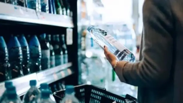 Жінка обирає мінеральну воду в магазині