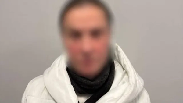 Жінка із розмитим обличчям у білій куртці та чорному шарфі на сірому фоні