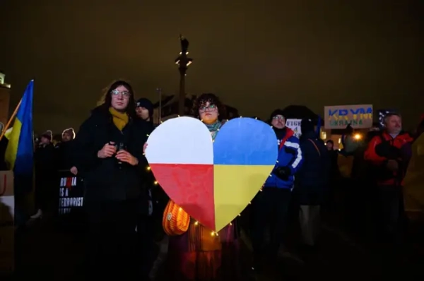 Навроцького вразив підрозділ ЗСУ, названий на честь УПА, він погрожує Зеленському 12 Вечірня акція підтримки: люди стоять на площі з прапорами і плакатами. У центрі – велике серце, поділене на кольори прапорів України та Польщі, як символ солідарності між країнами.