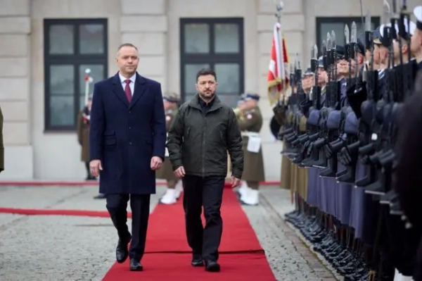 Навроцького вразив підрозділ ЗСУ, названий на честь УПА, він погрожує Зеленському 10 На червоній доріжці Навроцький і Зеленський у верхньому одязі йдуть поруч між рядами почесної варти військових із гвинтівками. Дія відбувається на подвір’ї урядової будівлі, де позаду видно прапори та солдатів у строю.