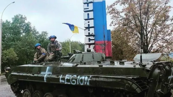 Двоє військових сидять на бронемашині