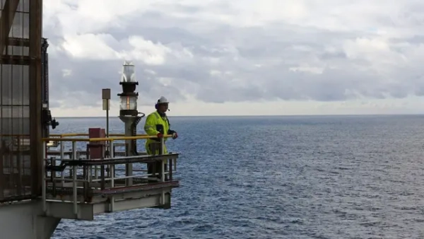 Чоловік дивиться вдалину з виступу на морській платформі