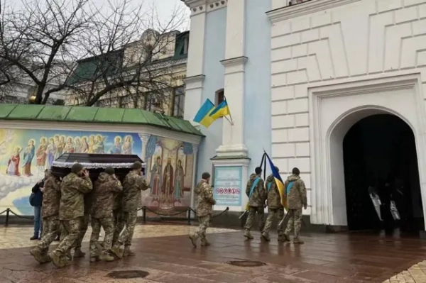 Військові несуть дві труни у ворота собору