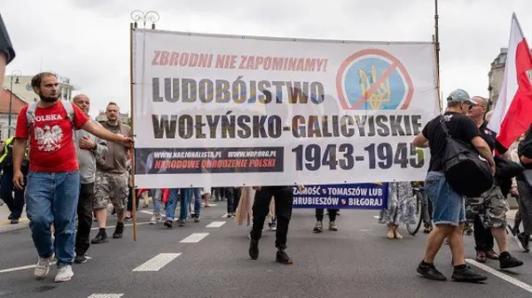 Протестувальники несуть банер з написом "Волинсько-галицький геноцид 1943-45 років" із зображенням перекресленого українського тризуба під час демонстрації у Варшаві, Польща, 12 липня 2026 року