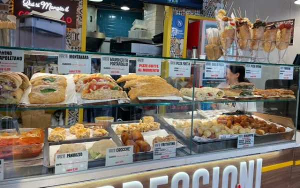 Продуктовий кіоск у Неаполі з полицями, заповненими бутербродами, макаронами, хлібом та смаженою їжею