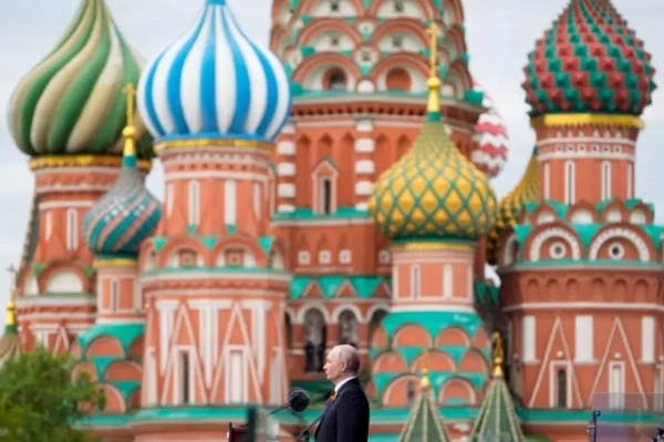 Володимир Путін перед мікрофоном, за ним — собор Василія Блаженного.
