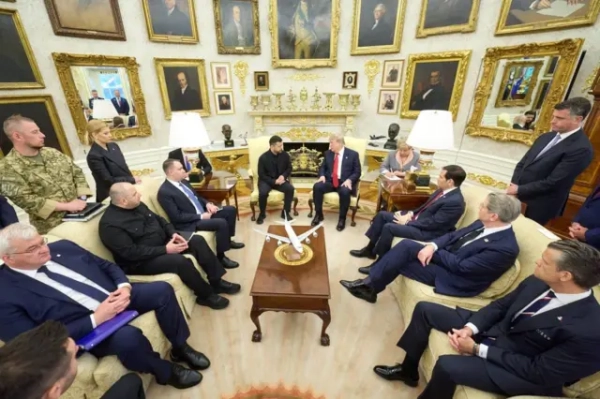 Зустріч делегацій у Білому домі: Трамп і Зеленський сидять у центрі кімнати, навколо них розмістилися радники та посадовці. Інтер’єр прикрашений численними портретами в золотих рамах, а на столі стоїть модель літака.