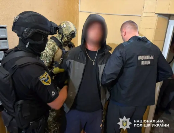 Чоловіка тримають за руки поліцейські. Його обличчя заблюрено