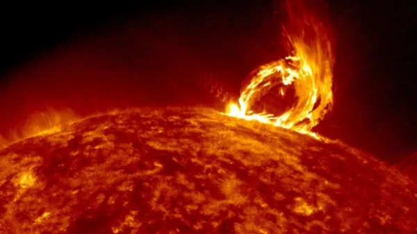 The image shows the fiery orange surface of the Sun, and to its right, a protrusion resembling an arc of flame extending from the surface. This is a coronal mass ejection – a sudden release of solar plasma and magnetic fields that the Sun emits into space.