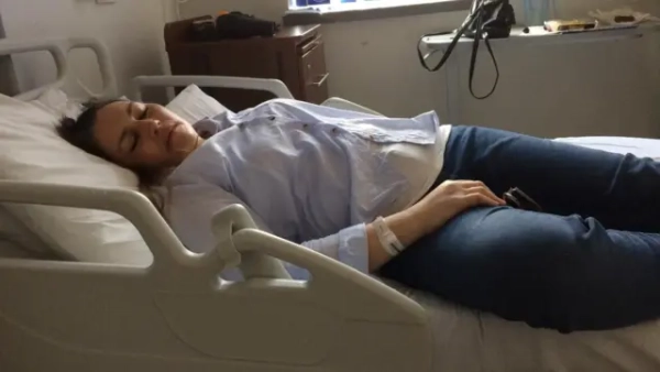 Жінка на лікарняному ліжку, в неї заплющені очі