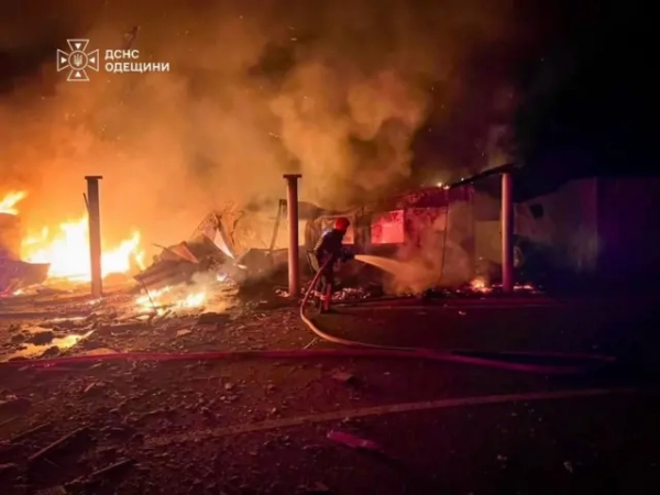 Пожежа на території прикордонного об'єкта після удару: рятувальник гасить вогонь, навколо – уламки та пошкоджені конструкції, у повітрі густий дим.