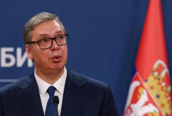 Вучич на тлі стіни та прапора Сербії