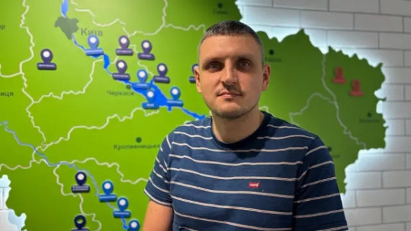 Як Росія вистежує цивільні кораблі в Чорному морі - звіт BBC 7 Чоловік у синьо-білій смугастій футболці стоїть перед картою України, яка світиться на стіні за його спиною.
