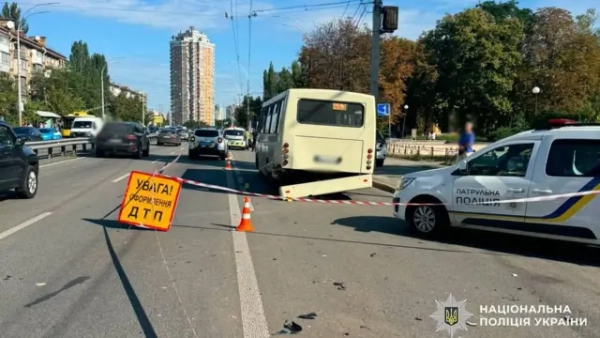 Місце дорожньо-транспортної пригоди на багатосмуговій міській дорозі. На проїжджій частині стоять маршрутний автобус та патрульний автомобіль поліції. Ділянка дороги огороджена сигнальною стрічкою та конусами, встановлено попереджувальний знак "Увага! Оформлення ДТП".