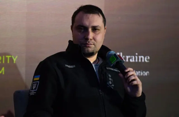 Буданов у темній формі сидить з мікрофоном в руках